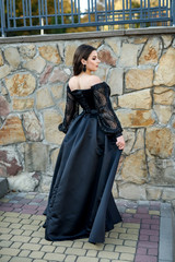 Fototapeta na wymiar Fashion smiling woman in black dress on a brick background. Fashion