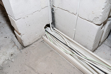 Layed installation of electric cables on the floor in a newly built house. Cables passing through the walls of the house.