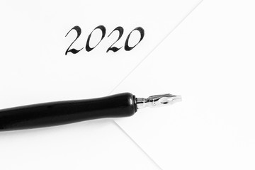 Sheets of white paper with 2020 handwritten numbers, next to a writing pen. Concept of plans for the year, to-do list. Minimalism, place for text.