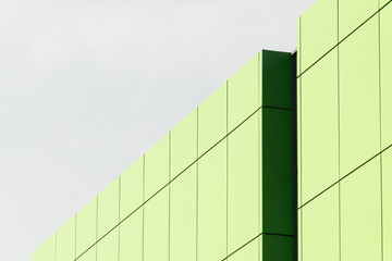 Fototapeta na wymiar Geometric color elements of the building facade with planes, lines, corners with highlights and reflections for the abstract background and texture of green, light green, blue colors. Place for text