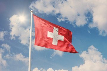 Flag of Switzerland, National symbol waving against cloudy, blue sky, sunny day