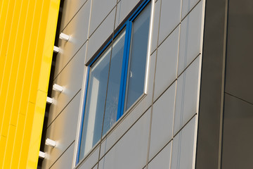 Fototapeta na wymiar Geometric color elements of the building facade with planes, lines, corners with highlights and reflections for the abstract background and texture of blue, yellow, orange, gray colors. Place for text