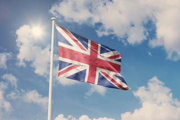Flag of UK, National symbol waving against cloudy, blue sky, sunny day