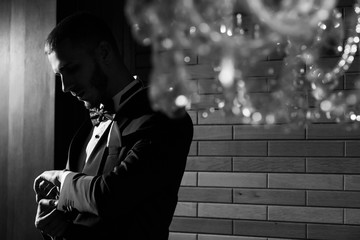 Groom with trendy beard. Wedding.  Sexy groom in tuxedo and bow tie posing.Handsome groom getting dressed and preparing for the wedding. Rich man at wedding day. Black and white photo.