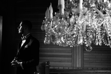 Groom with trendy beard. Wedding.  Sexy groom in tuxedo and bow tie posing.Handsome groom getting dressed and preparing for the wedding. Rich man at wedding day. Black and white photo.