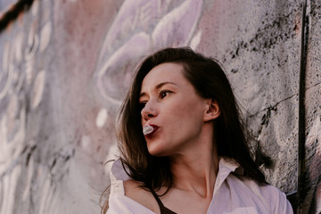 Woman with long hair on street. Red brick wall behind model. Street style fashion outfit. Urban lifestyle outfit. Plaid shirt, white t-shirt. Rebel girl. Showing different emotions. Sexy red lips.