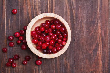Fresh cranberry berries in wooden bowl on rustic table