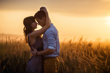 Loving couple middle of the wheat field at sunrise. A young couple in love touched hands on the first date. Loving couple has a happy relationships.