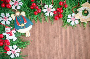 Green spruce branches. Brown wooden background. White, red, multi-colored Christmas toys. Decorations for Christmas tree made of wood and ceramics. Festive fun concept. Congratulatory backdrop. 