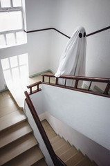 Ghost covered with a white ghost sheet on the stairs of an abandoned psychiatric hospital....