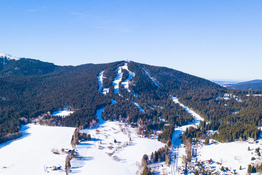Aerial view of Spicak mountain with ski slopes near Zelezna Ruda. Winter resort in national park Sumava, Czech republic, European union.