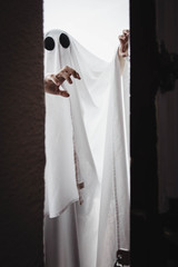 Ghost covered with a white ghost sheet behind the door. Halloween Concept