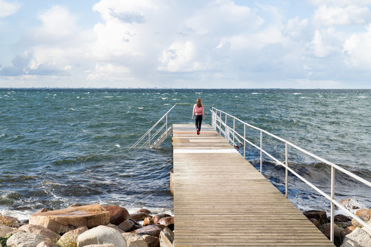 Rear view of woman standing on ocean pier