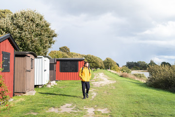 Man wearing yellow jacket walking by beach huts