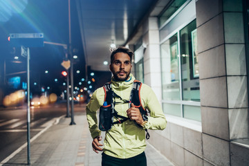 Fototapeta na wymiar Night city fitness. Good looking man jogging on street.