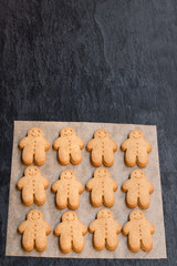 Set of baked gingerbread man cookies on black stone background