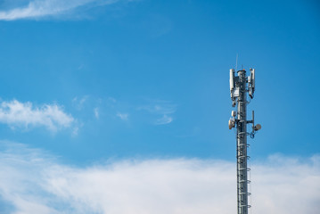 Obraz premium Cellular Base Station or Base Transceiver Station. Telecommunication tower. Wireless Communication Antenna Transmitter. 3G, 4G and 5G Cell Site with cloudy blue sky.