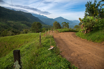 Dirt road in countryside landscape with mountains in Colombia.