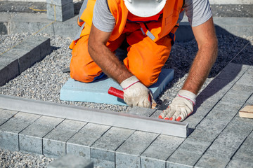 Construction worker on knees leveling paving bricks