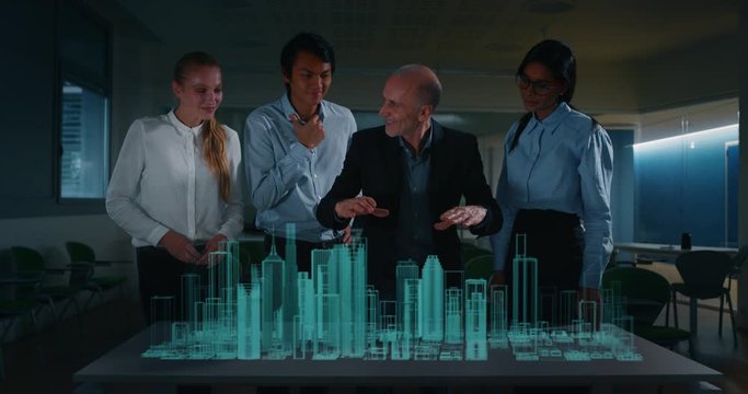 A group of modern designers are using a futuristic sophisticated technology screen with augmented reality holograms for a new project realization in an office.