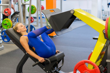blonde trains leg and abdominal muscles on a sports simulator