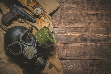 Post apocalypse soldier table concept background. Gas mask, gun, compass and old military wear on...