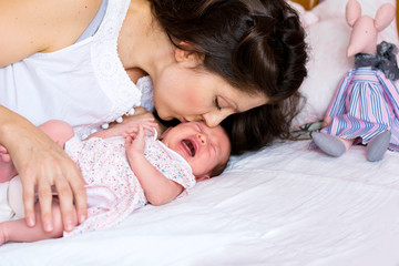 Fototapeta na wymiar Mother Kissing and Trying to Calm Down her Crying Newborn Baby