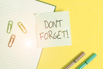 Word writing text Don T Forget. Business photo showcasing used to remind someone about important fact or detail Empty blue paper with copy space paper clips and pencils on the yellow table