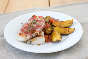 European hake with rosemary and garlic in bacon. Grilled vegetables with italian seasoning and baked potatoes