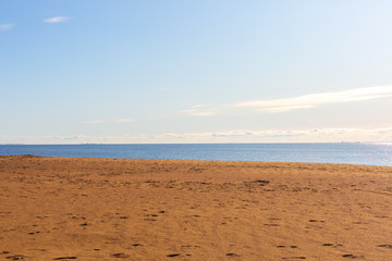 Deserted seascape. Minimalism. Strip of orange sand, sea and clear blue sky