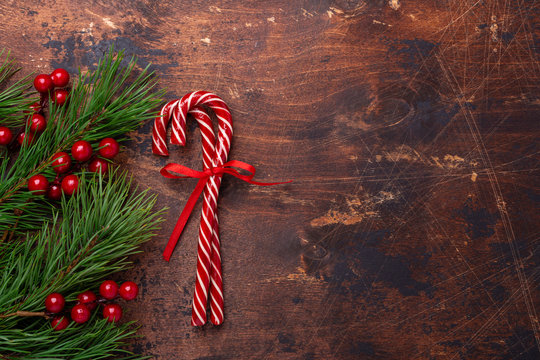 Candy canes with fir tree branches on wooden background. Christmas composition. New Year concept. Top view - Image