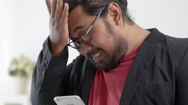portrait of disapointed businessman receiving text message on his smartphone