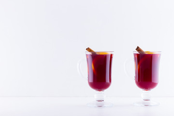 Glass of hot mulled wine with spices on white background. Christmas mulled wine with orange, star anise and cinnamon. Two glasses of winter Christmas drink