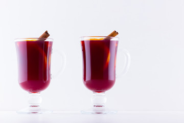 Glass of hot mulled wine with spices on white background. Christmas mulled wine with orange, star anise and cinnamon. Two glasses of winter Christmas drink