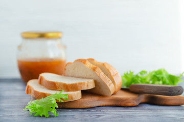 Sliced bread and salad greens on a rustic kitchen table.