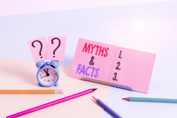 Conceptual hand writing showing Myths And Facts. Concept meaning usually traditional story of ostensibly historical events Mini size alarm clock beside stationary on pastel backdrop