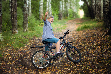 Fototapeta na wymiar Happy boy on a bicycle in park studies to ride sharply braked on a dirt.