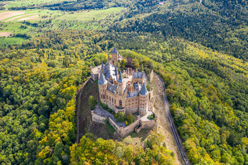 Aerial panorama of Burg Hohenzollern (Hohenzollern castle) with hills and villages surrounded by forests with beautiful foliage