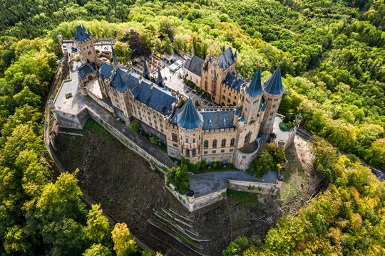 Aerial panorama of Burg Hohenzollern (Hohenzollern castle) with hills and villages surrounded by forests with beautiful foliage