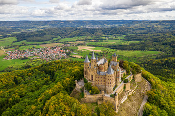 Aerial panorama of Burg Hohenzollern (Hohenzollern castle) with hills and villages surrounded by forests with beautiful foliage