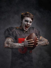 A young man in the makeup of a zombie in the form of an American football player.