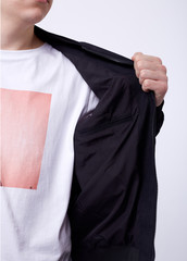 Young man in jeans, black bomber jacket on white background.