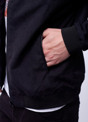 Young man in jeans, black bomber jacket on white background.