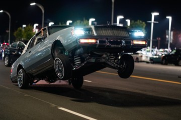 Closeup shot of a retro car with only the back wheels on the ground in a street at night