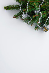 Vertical greeting card. Festive decoration with copy space for wishes. Green christmas tree branches, silver baubles, chain and little present.