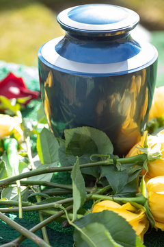 Close up on an urn with yellow roses, at an outdoor funeral