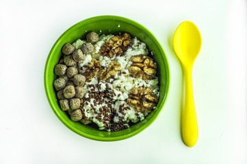 healthy breakfast concept. good food. cottage cheese with bran, flaxseeds and walnuts. green plate. yellow spoon. Suitable for illustrating a recipe, an article on malnutrition.