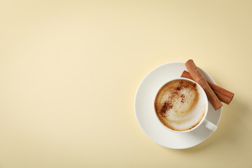Cappuccino with cinnamon on beige background, space for text