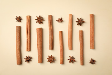 Flat lay with cinnamon sticks and anise stars on beige background, space for text