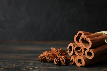 Cinnamon sticks and anise stars on wooden background, space for text